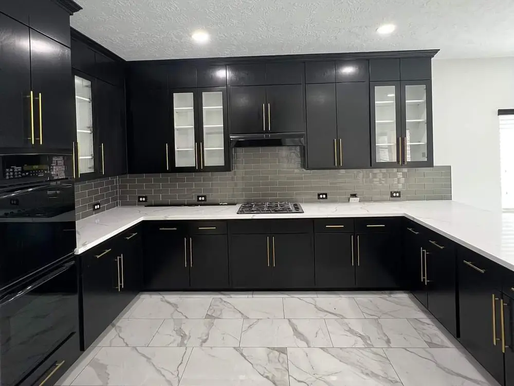 Kitchen with black cabinets, gold pulls and white stone counters