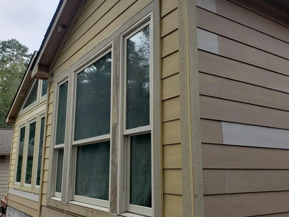 New primed boards fitted into existing lap siding beside the window trim