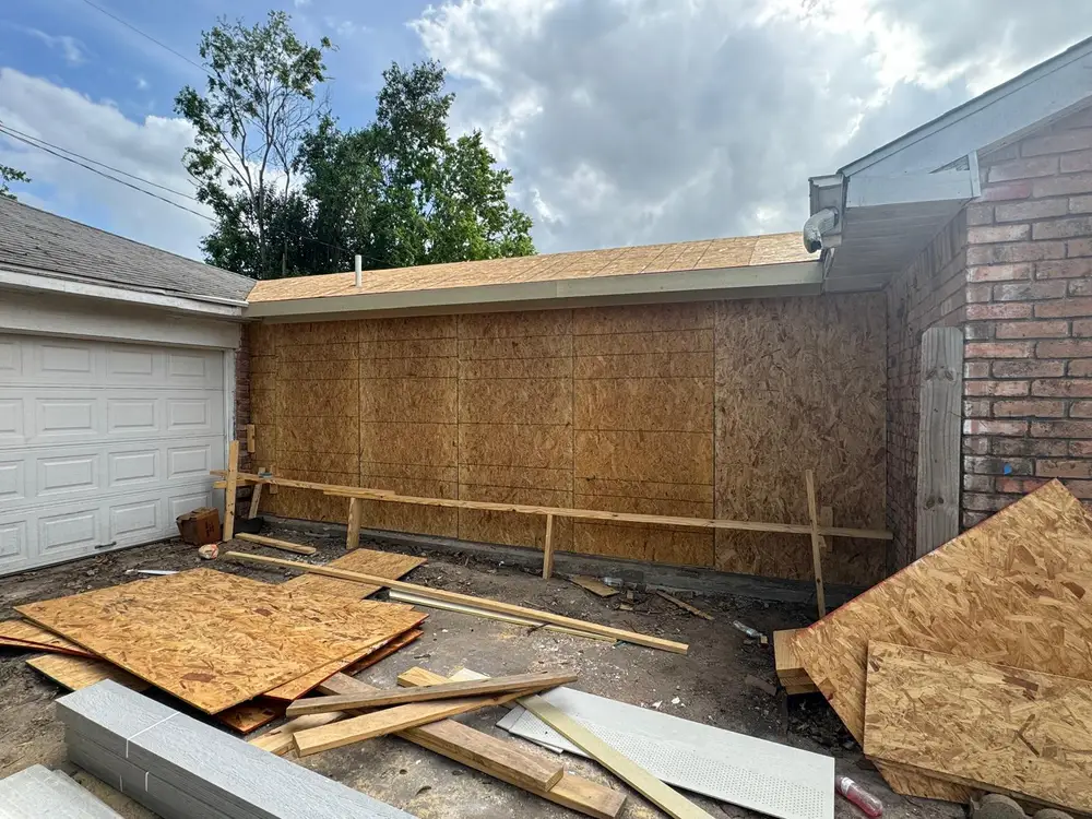 Exterior wall rebuilt with new OSB sheathing beside a brick wall