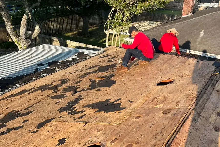 Two crew members stripping a Houston roof back to bare decking