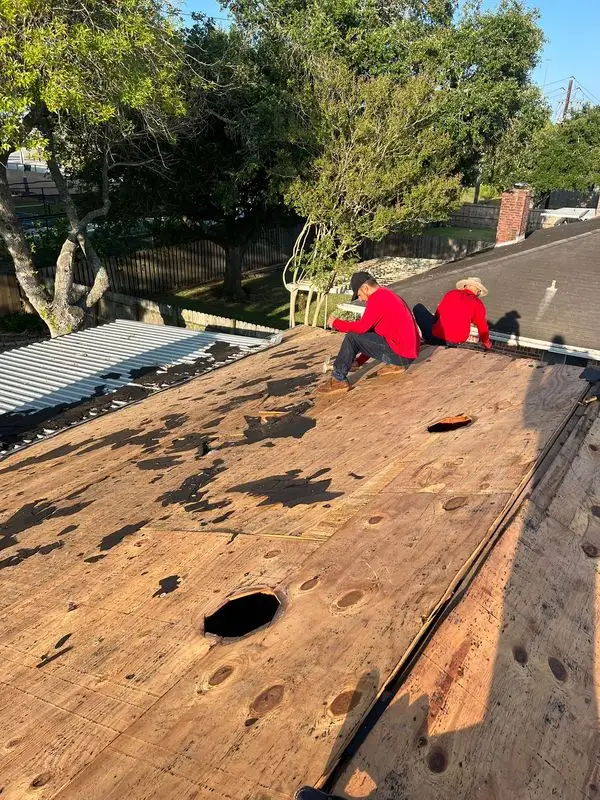Two roofers stripping old shingles down to damaged decking