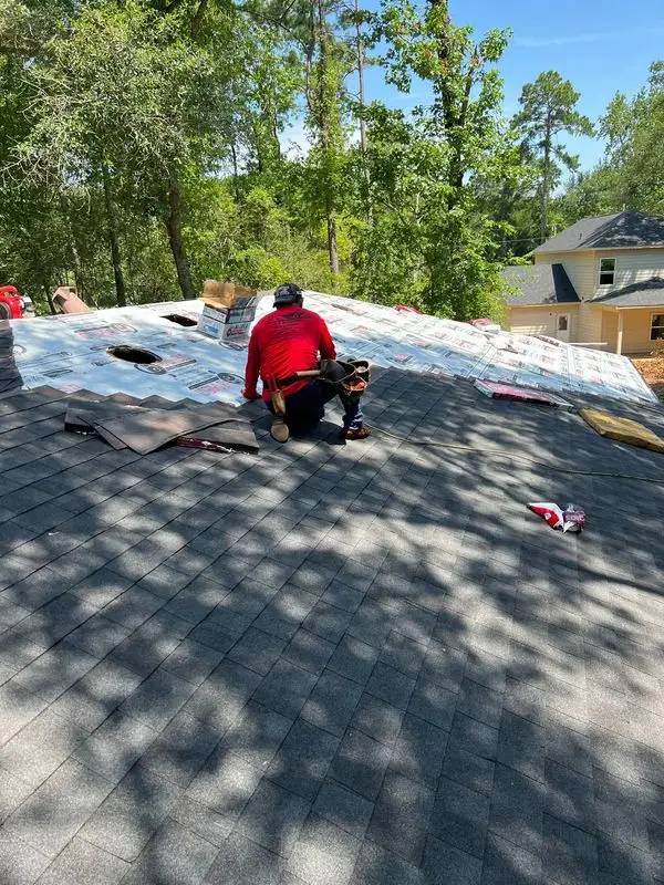 Roofer working on a roof with synthetic underlayment and new shingles