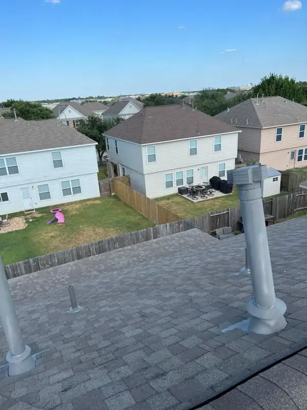 Vent pipes on a new shingle roof with houses behind