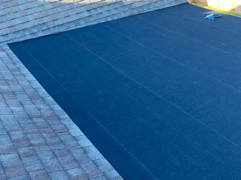 New underlayment beside existing shingles on a repaired section of roof