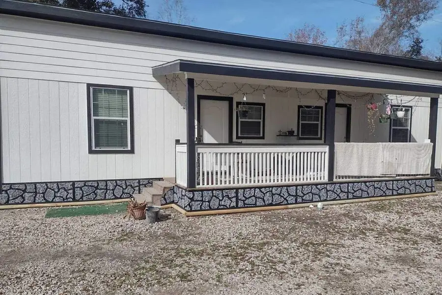 Single-story home with white board and batten siding, black trim and a covered porch
