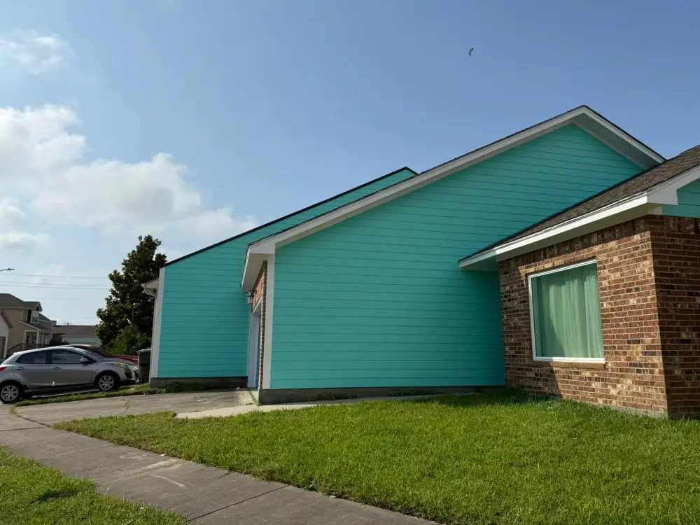 Teal lap siding with white trim on a brick house